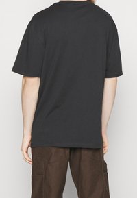 T-shirt noir à coupe ample et manches courtes, fabriqué en coton doux, avec un col rond côtelé et un ourlet droit.