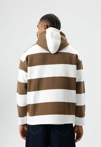 Hoodie met bruine en witte horizontale strepen, gemaakt van dikke stof, met een textuur en een capuchon met trekkoord.