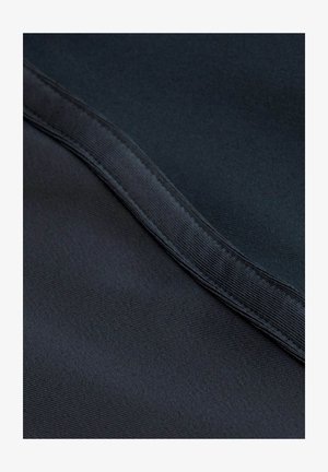 Közelkép sötét szövetből, sima textúrával, egy átlósan futó varrással a keret mentén.