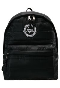 Sac à dos noir matelassé avec poche avant zippée, fermeture à double zip, et écusson circulaire avec couronne de laurier blanche et texte "hype.".