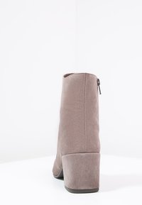 Šedá nubuková kotníková bota s texturovaným povrchem, kulatou špičkou a vysokým blokovým podpatkem. Obsahuje boční zip pro snadné obouvání.