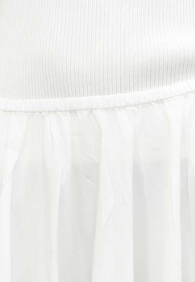 Λευκό ένδυμα με ριμπ πλεκτό πάνω μέρος και μαζεμένο διαφανές ύφασμα από κάτω, ραμμένο στη μέση.