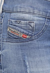 Jeans i ljusblå denim med en liten ficka som har en etikett med texten "Diesel Industry." Mjuk textur med en lätt sliten look.