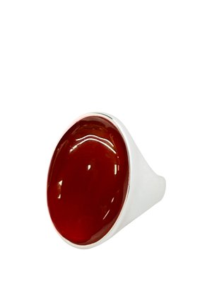 Srebrny pierścionek z dużym gładkim owalnym ciemnoczerwonym kamieniem szlachetnym osadzonym na prostym pasku na białym tle.