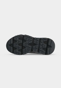 Semelle de chaussure en caoutchouc noir avec des rainures profondes, des motifs géométriques et le nom de la marque embossé près du centre.