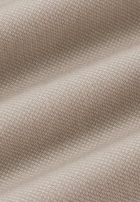 Teksturowana tkanina w neutralnym beżowym odcieniu, z plecionym wzorem w różnych odcieniach, tworzącym głębię i subtelną wizualną interesującość.