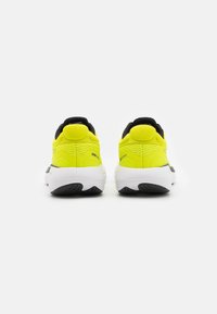 Zapatillas de running de color amarillo neón con detalles en negro, que cuentan con talones acolchados, una parte superior texturizada y una suela blanca con un dibujo de banda.