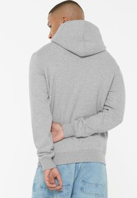 Gray hooded sweatshirt made of soft cotton blend, featuring ribbed cuffs and hem, with a relaxed fit and detailed stitching.