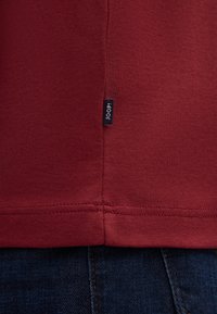 Bordeauxfarbenes T-Shirt aus weichem Material, mit sichtbarem Etikett und "JOOP!"-Logo sowie sauberem Stich entlang des Saums.