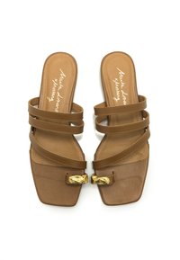 Chanclas marrones con punta cuadrada, que presentan tres correas y un acento decorativo de hardware en tono dorado en la parte frontal, textura suave.