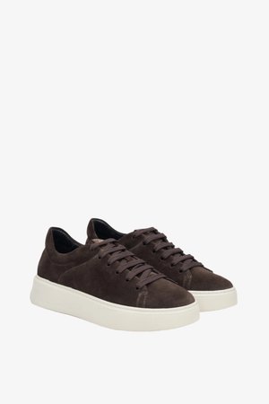 Braune Wildledersneaker mit weißer Gummisohle, runder Zehenform, Schnürdesign und strukturierten Akzenten an der Oberseite. Minimalistischer Stil.