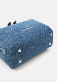 Denim påse med rektangulär form, ljusblå färg, silverfärgade nitar och "VALENTINO"-logotyp på framsidan. Har ett dragkedjestängning med blå detaljer.