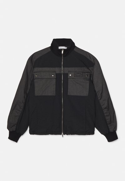 Casaco bomber preto e cinza com fecho éclair na frente, dois bolsos no peito, gola e punhos canelados, e uma mistura de tecidos lisos e texturizados.