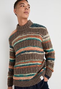 Suéter marrón de punto con franjas horizontales multicolores en naranja, verde azulado y crema. Cuello alto con un ribete acanalado y detalles de patrón texturizado.