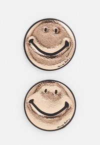 Broche de imagem de sorriso metálico, tom dourado com acabamento texturizado, contorno preto, dois designs visíveis, apresentando expressões faciais simples e branding.