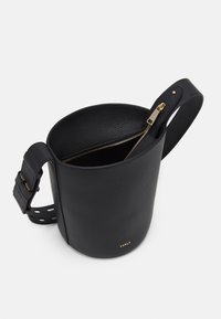 Svart läderväska med texturerad yta, guldfärgad dragkedja och en bred, justerbar rem med urklippta detaljer. Märkesnamn präglat.