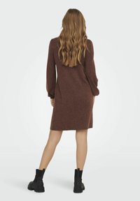 Abito lavorato a maglia color bordeaux con maniche lunghe, vestibilità comoda e orlo all'altezza del ginocchio. Abbinato a stivali neri alla caviglia, con pannelli laterali elasticizzati.