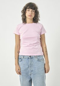 Rosa Baumwoll-T-Shirt mit klassischem Rundhalsausschnitt und kurzen Ärmeln, kombiniert mit hellblauen High-Waist-Jeans aus Denim. Einfaches, figurbetontes Design.
