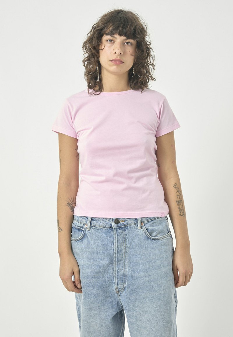 Rosa Baumwoll-T-Shirt mit klassischem Rundhalsausschnitt und kurzen Ärmeln, kombiniert mit hellblauen High-Waist-Jeans aus Denim. Einfaches, figurbetontes Design.