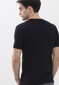 T-shirt nera a maniche corte realizzata in tessuto morbido, con un classico colletto rotondo e un design aderente, senza pattern o accenti visibili.
