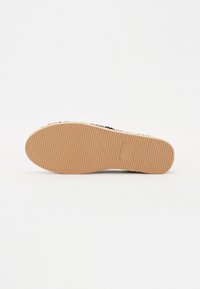 Chaussure textile noire avec un dessus à motif, dotée d'une semelle en caoutchouc avec une surface texturée et rainurée, de couleur marron clair unie.
