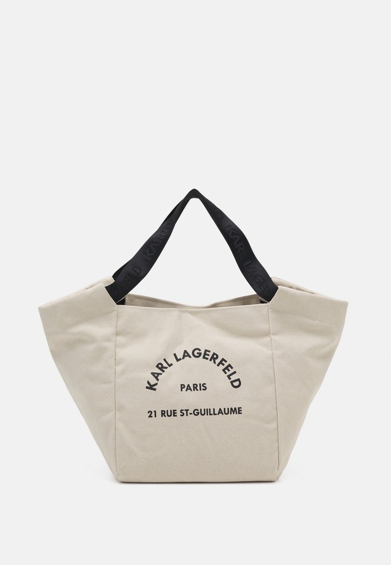 Borsa tote beige con testo nero "KARL LAGERFELD PARIS 21 RUE ST-GUILLAUME" sul davanti e manici neri con il nome del marchio impresso.