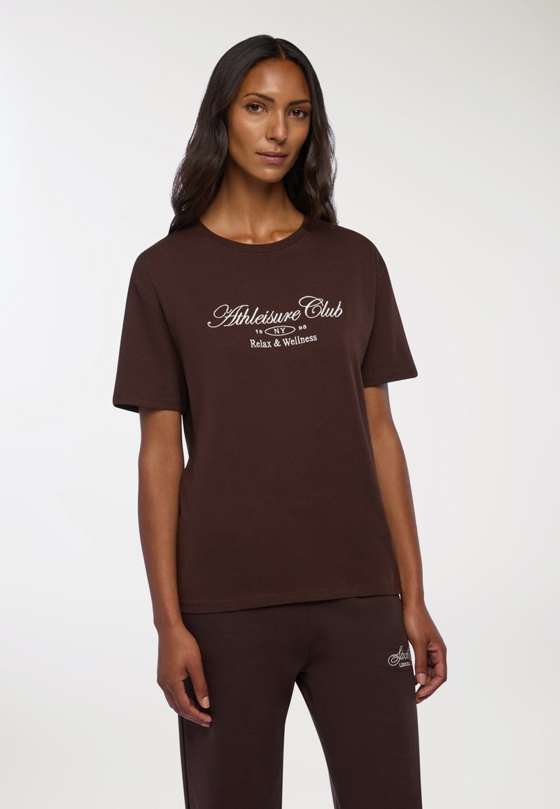 Brązowy bawełniany t-shirt z krótkim rękawem i okrągłym dekoltem, z białym nadrukiem "Athleisure Club" oraz "Relaks & Wellness."