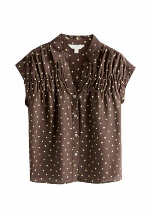 Bruine blouse met korte mouwen en gele polka dots, knopen aan de voorkant, kraag en geplooide details over de borst en schouders.