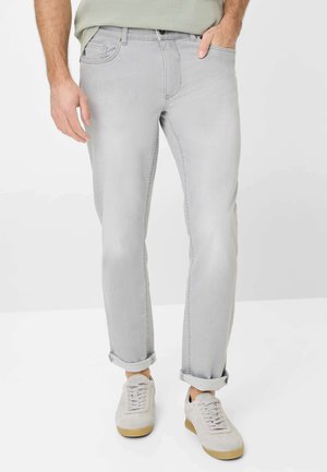 Lichtgrijze denim jeans met een rechte pasvorm, opgerolde mouwen en subtiele stiksels. Gecombineerd met lichtgrijze sneakers.