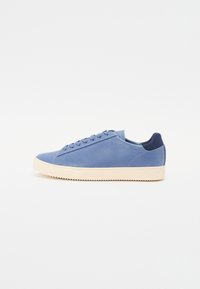 Blue leather sneakers with a smooth finish, round toe, and flat light-colored rubber sole. Features tonal laces and a navy back tab.