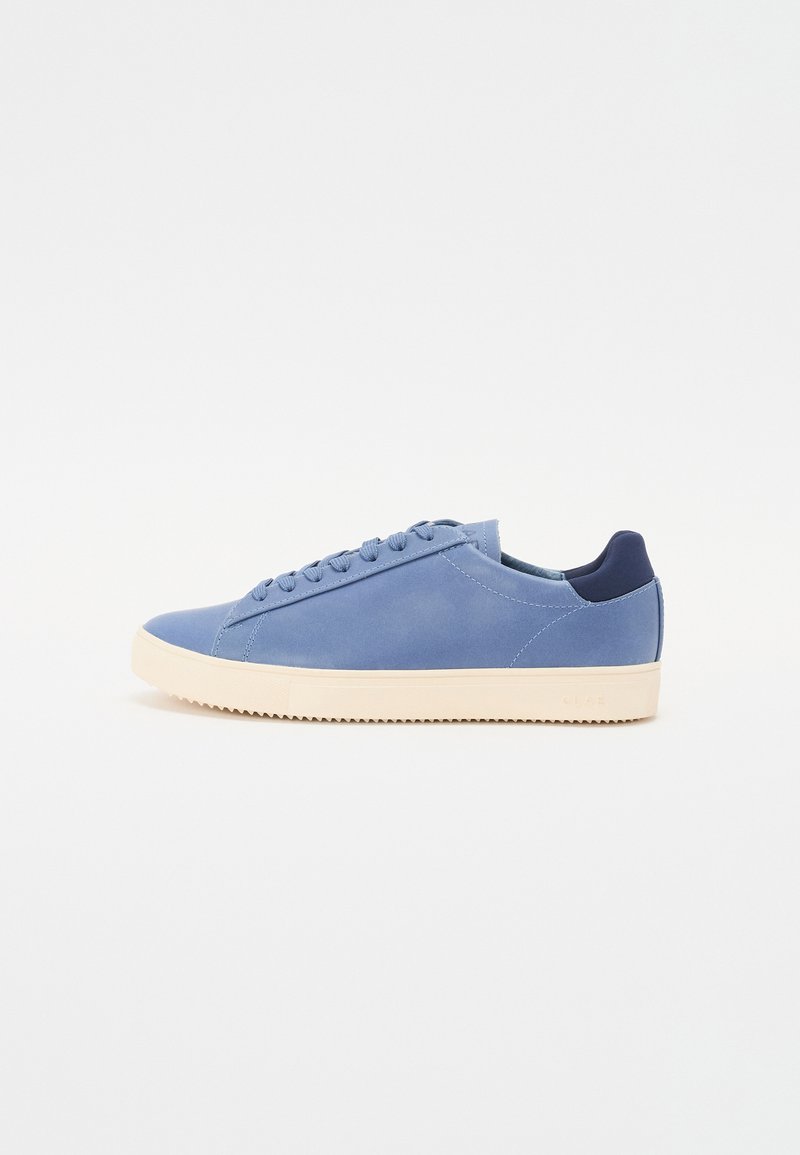 Blue leather sneakers with a smooth finish, round toe, and flat light-colored rubber sole. Features tonal laces and a navy back tab.