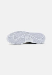 Scarpa con suola in gomma bianca caratterizzata da un motivo a spina di pesce, contrassegnata dal logo "PUMA". La parte superiore è probabilmente in materiale sintetico con una superficie liscia.