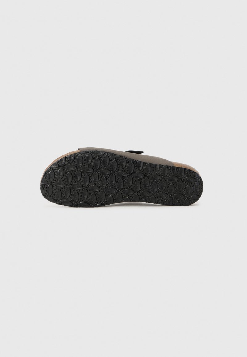 Semelle de chaussure en caoutchouc noir avec un motif de grip texturé et un bord brun clair. La semelle est plate avec des courbes arrondies et peu d'éléments décoratifs.