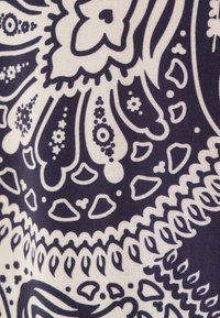 Marineblauwe en crèmekleurige stof heeft verfijnde paisleypatronen met bloemachtige en geometrische vormen, en vertoont een gladde textuur.