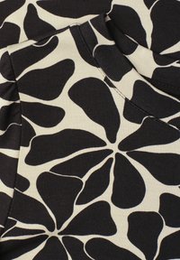 Black and white fabric with large abstract floral pattern and visible stitching details on folded textile.