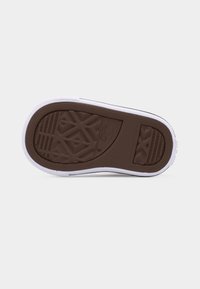 Καφέ λαστιχένια σόλα με γεωμετρικό ανάγλυφο μοτίβο και λευκή μεσαία σόλα, εμφανιζόμενη από κάτω σε φωτεινό φόντο.