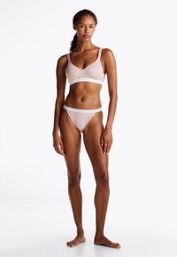 Lys rosa bralette og matchende tanga-sett laget av myk stoff. Bralette har justerbare stropper og logo-accentuert midje.