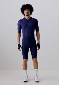 Navy Radtrikot mit kurzen Ärmeln und Shorts, figurbetontes Design, aus glattem Stoff, ergänzt durch schwarze Handschuhe und weiße Socken.