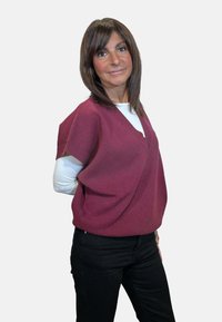 Maglione bordeaux lavorato a maglia con scollo a V, maniche corte e vestibilità ampia, abbinato a pantaloni neri. Texture liscia e design casual.