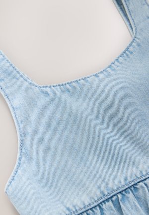 Tessuto di denim azzurro con sottili righe verticali, caratterizzato da uno scollo a barchetta e dettagli arricciati all'orlo. Vista ravvicinata della trama.