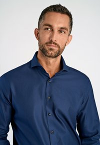 Donkerblauw gestructureerd overhemd met een button-down kraag en zwarte knopen. Strak aansluitend ontwerp met lange mouwen, dat subtiele patronen toont.