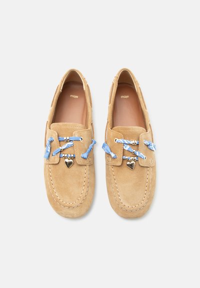 Ζευγάρι ταμπά μοκασίνια σουέτ με μπλε κορδόνια κορδέλας περασμένα από ασημί ρουμπάκια και μικρές ασημένιες καρδιές ως διακοσμητικά σε κάθε παπούτσι.