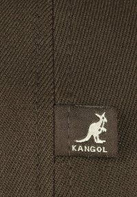 Tessuto marrone con una texture a coste diagonali, caratterizzato da una patch del logo Kangol bianca con un design di canguro.