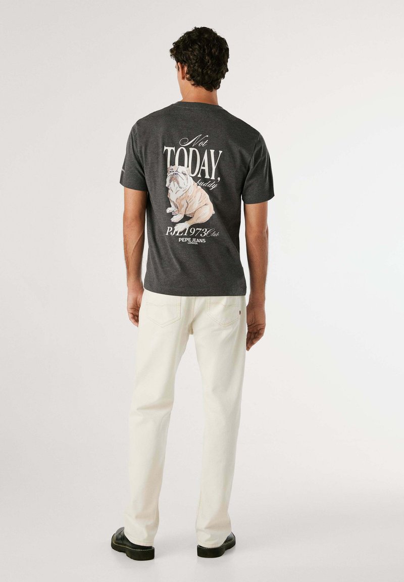 Grijze katoenen T-shirt met een bulldogafbeelding en tekst op de achterkant, gecombineerd met witte denim broek en zwarte schoenen.