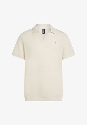 Krém színű rövid ujjú galléros póló, texturált anyagból, V-nyakú gallérral és kontrasztos gallérszegéllyel. Apró logó részlet az elején.