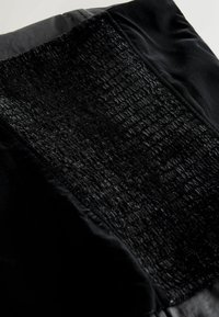 Musta kangas, millel on tekstureeritud, läikiv pind ja siledad alad. Omab mati ja läikiva viimistluse kombinatsiooni, millel on erinev paksus.