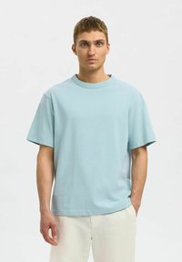 Ljusblå T-shirt med kort ärm i mjuk bomull, med rund hals och avslappnad passform. Slät textur utan synliga mönster.