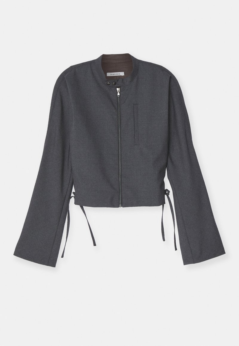 Giacca grigia cropped con colletto alto, zip frontale e maniche lunghe a campana. Presenta lacci laterali e un tessuto lucido e strutturato.