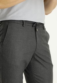 Grijze, gestructureerde broek met een trekkoord in de taille, schuine zakken en een getailleerde pasvorm, ontworpen voor comfort en veelzijdigheid.