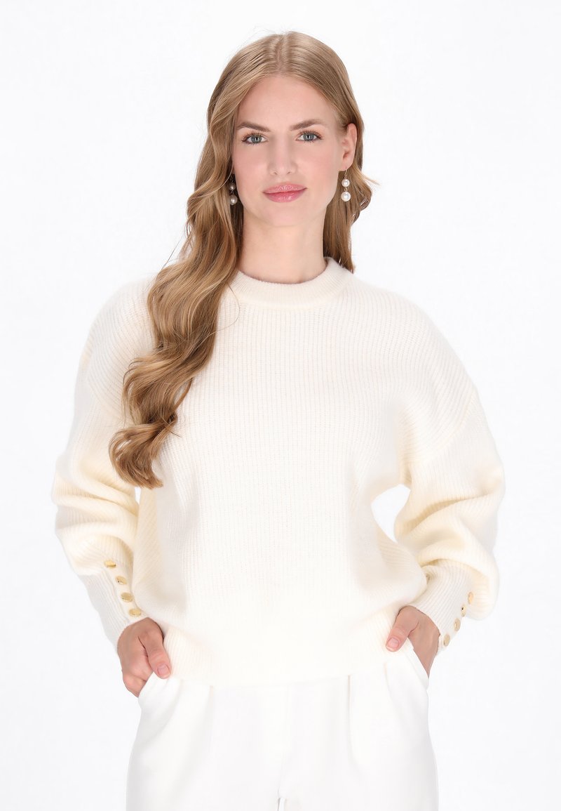 Maglione bianco lavorato a maglia con colletto rotondo, spalle scese e sottile costina, con dettagli a bottoni sui polsini.
